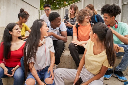 Preview: Multi-ethnic group of happy students on a break. Young people laugh sitting on the stairs