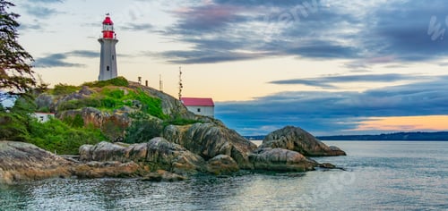 Preview: Lighthouse on a rocky coast during a cloudy sunset.