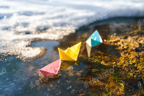 Preview: Multicolored paper boats. Colorful pink yellow blue orange ships in big spring snow puddle on