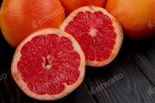Preview: close-up view of cut and whole grapefruits on black background