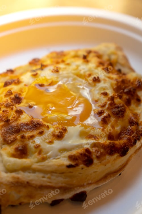 Preview: Traditional Georgian cuisine. Ajara khachapuri on paper plate. Filled with cheese and topped with