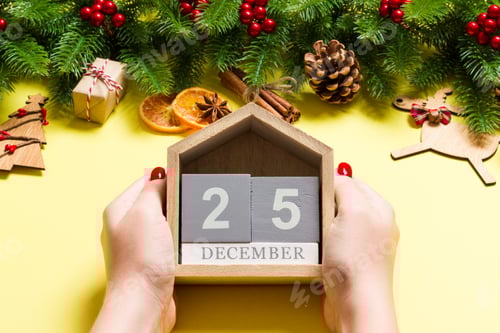 Visualização: Vista superior das mãos femininas segurando o calendário em fundo amarelo.