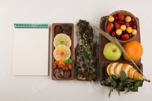 Preview: Berries, fruit mix and herbs in a wooden platter with a notebook aside
