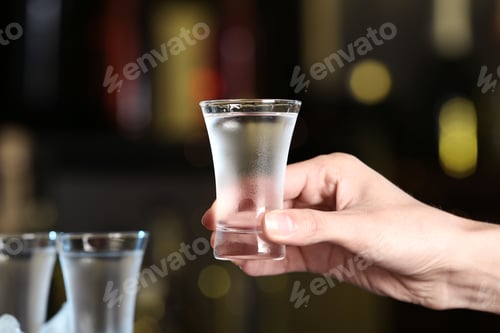 Preview: Woman holding shot of vodka on blurred background, closeup