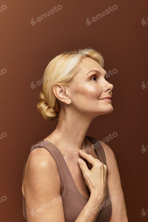 Preview: Elegant senior woman appreciating her beauty and wisdom in warm light