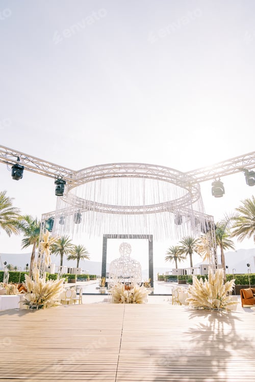 Preview: Round stage decorated with bouquets of flowers with spotlights on rectangular stands against the