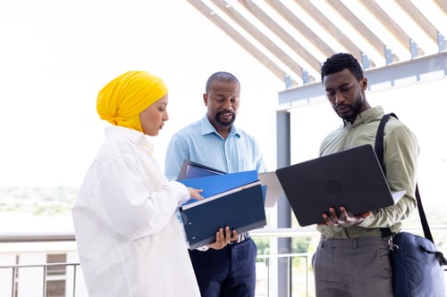 Preview: Happy diverse business people discussing and holding documents outside office