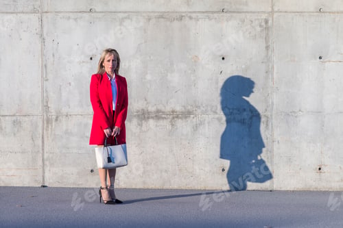 Preview: Blonde woman wearing red jacket and black shirt standing in the city