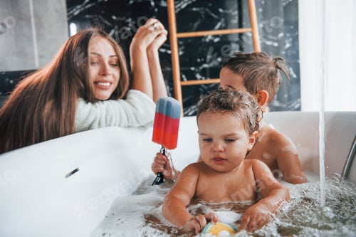 Preview: Young mother helps her son and daughter. Two kids washing in the bath