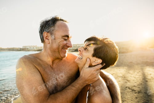Preview: Happy senior couple having a romantic moment on the beach at sunset during summer vacations