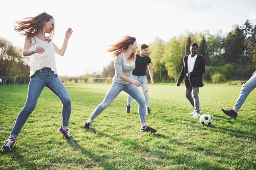 Preview: A group of friends in casual outfit play soccer in the open air. People have fun and have fun
