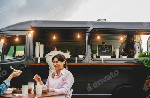 Preview: Happy people having fun eating and drinking outdoor at food truck restaurant - Focus on man head