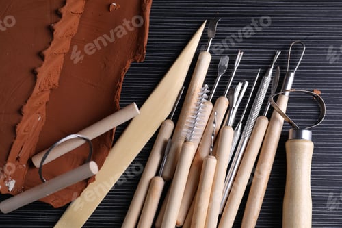 Preview: Clay and set of modeling tools on dark gray wooden table, flat lay