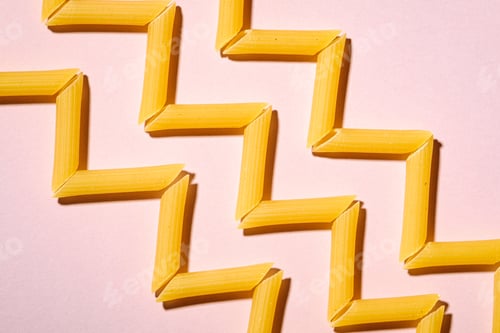 Preview: Italian pasta, raw penne tube macaroni zigzag pattern on pink background