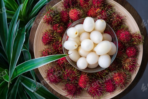 Preview: Rambutan, Malaysian sweet delicious fruits in bowl and bamboo plate in the balcony garden.