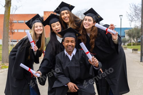 Preview: Happy multiethnic students celebrating graduation holding diplomas