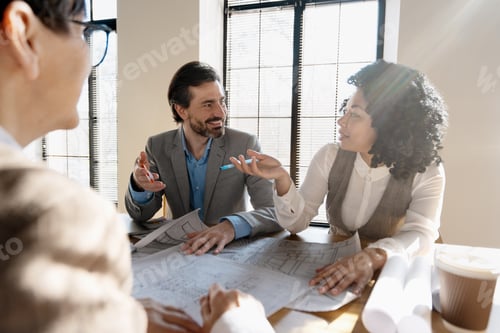 Preview: Architects discussing blueprints during a meeting in the office