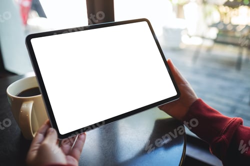 Preview: Mockup image of a woman holding digital tablet with blank white desktop screen in cafe