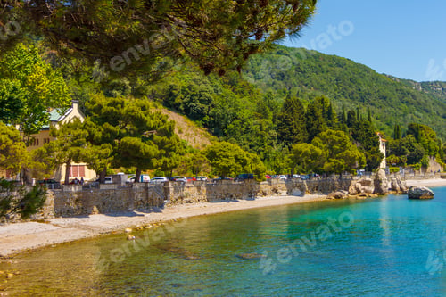 Preview: Amazing view on the seaside beach with azure water, yellow sand and a small rock in the corner of