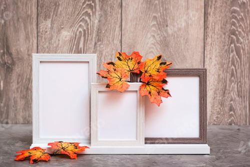Preview: Ready Mock up. Three empty photo frames on a stand and orange maple leaves stand on a table.