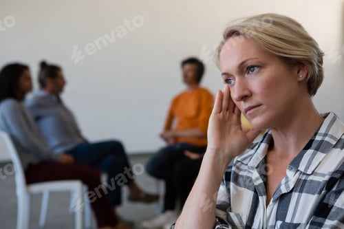 Preview: Worried woman with head in hand while friends discussing in background