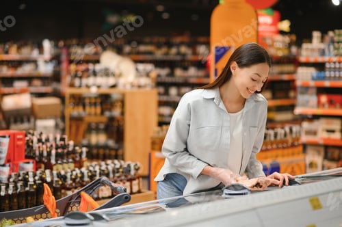 Preview: Young smiling happy woman 20s in casual clothes shopping at supermaket store with grocery cart