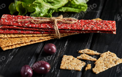 Preview: Beetroot and rye flour crackers with vegetables for making snacks on a black background.