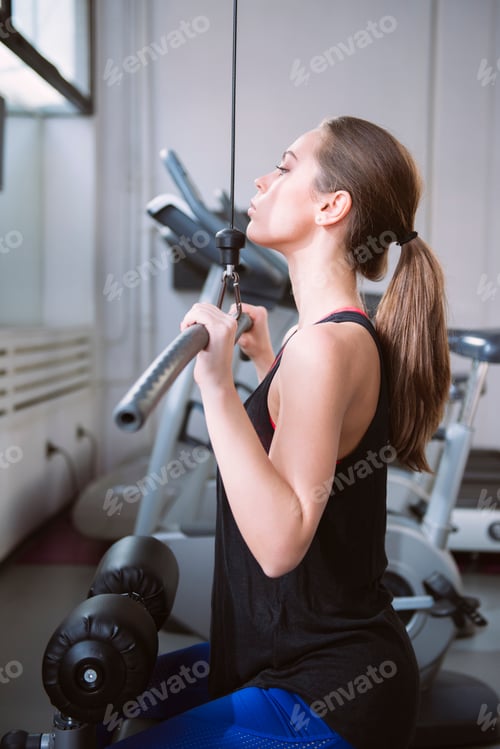 Preview: Young woman doing exercises on a machine at the gym