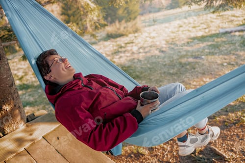 Preview: Person Relaxing in Hammock with Drink Outdoors