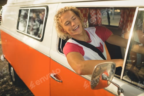 Preview: Smiling young man sitting in camper van