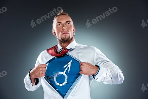 Preview: Businessman, Acting Like A Super Hero Or Superman And Tearing His Shirt Off On A Gray Background