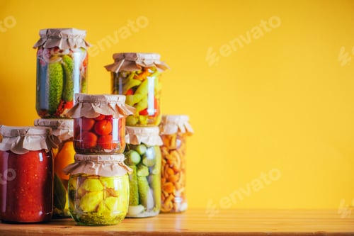 Preview: Preserved vegetables in glass jars on orange background. Copy space. Healthy fermented food concept