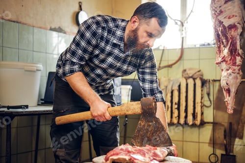 Preview: Bearded butcher cuts meat with axe.