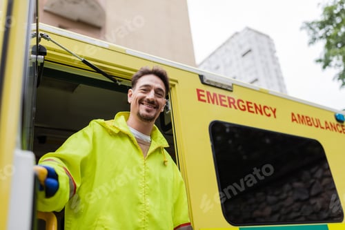 Preview: Smiling paramedic looking at camera near ambulance vehicle with open door on street