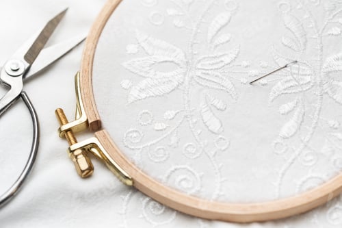 Preview: The process of embroidering a shirt with white threads on white fabric.