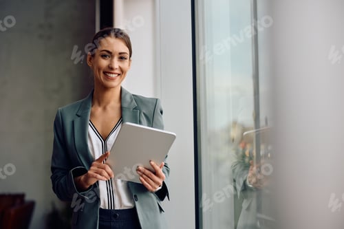 Preview: Happy businesswoman working on digital tablet in the office and looking at camera.