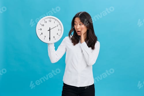 Preview: Shocked cute Asian businesswoman in classic office dress code with watch reminds about deadline