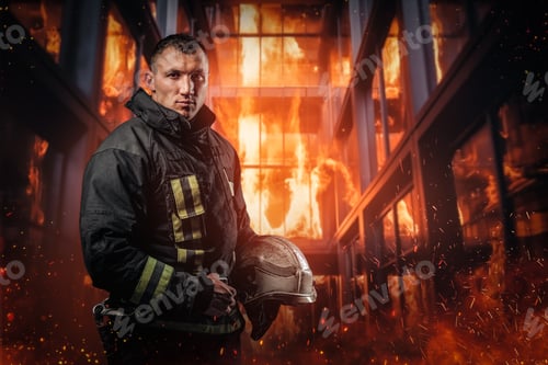 Preview: Firefighter in protective uniform stands amidst billowing flames and smoke