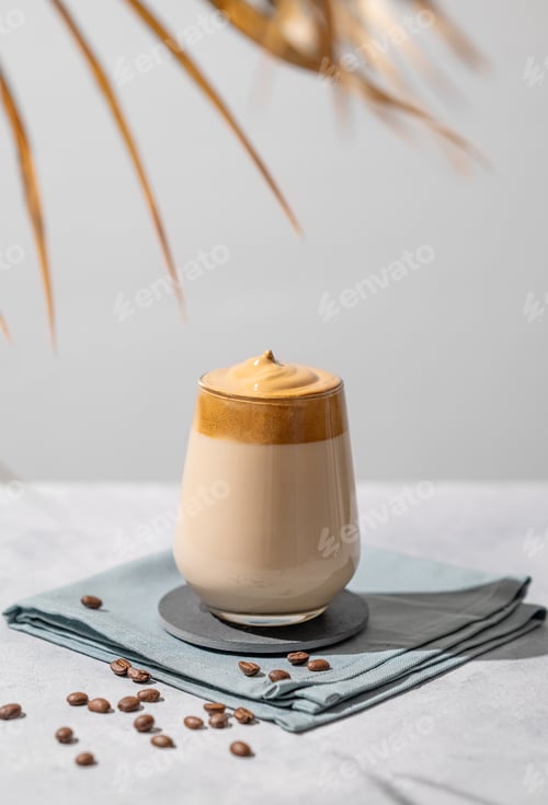 Preview: Dalgona coffee. Whipped instant coffee in a glass with beans on a light background.