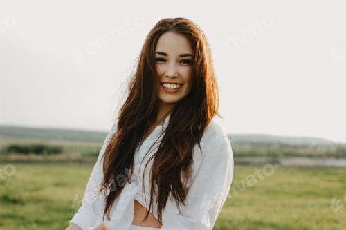 Preview: Portrait of beautiful carefree long hair asian girl in the white clothes on field at sunset