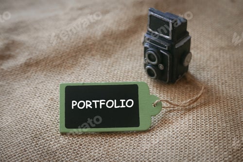 Preview: A miniature of a black vintage camera together with a wooden tag written with Portfolio.