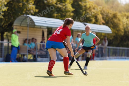 Preview: Young women compete in a hockey match on an outdoor field during summer