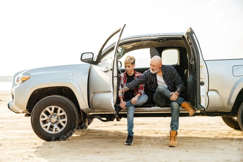 Vista previa: Smiling father and his son sitting in a car trunk