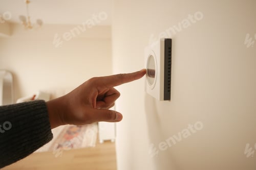 Preview: Hand Adjusting Smart Thermostat on White Wall for Optimal Home Temperature Control