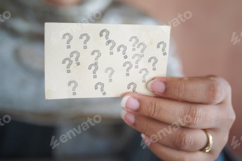 Preview: Holding a card with multiple question marks in a thoughtful moment