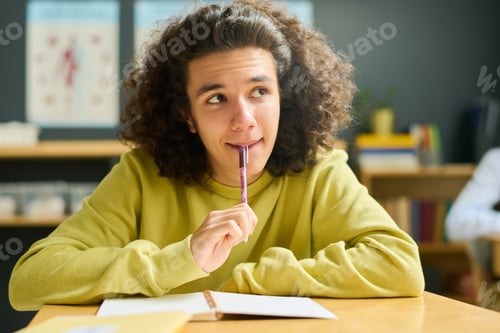 Preview: Clever teenage guy in casualwear looking at teacher or blackboard at lesson