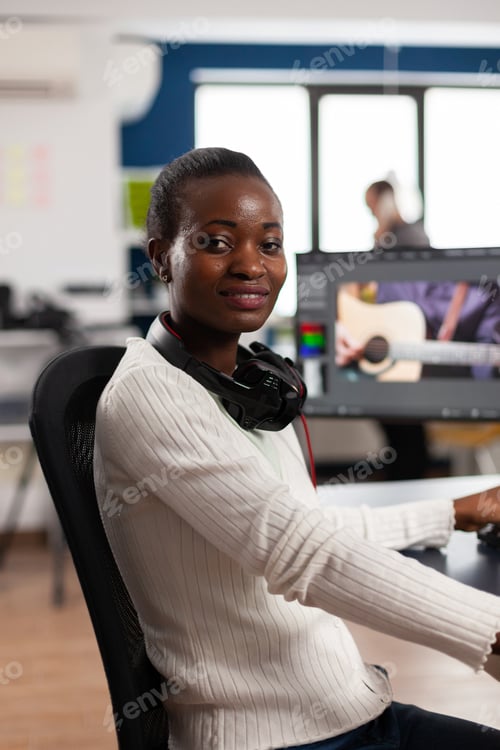 Preview: African video editor looking at camera smiling editing video project