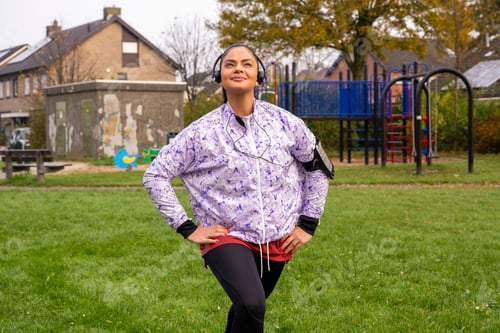 Preview: Healthy woman stretching listening to music at the public park