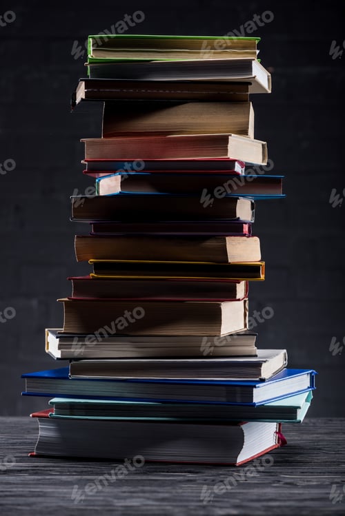 Preview: High stack of books on dark wooden background