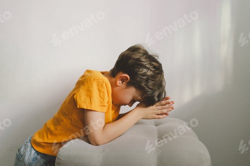 Vista previa: A boy in an orange T-shirt prays at home. Concept for faith